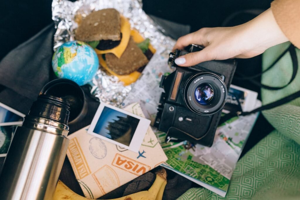 Capture memories with a vintage camera amid travel essentials like a map, snacks, and polaroid photos.